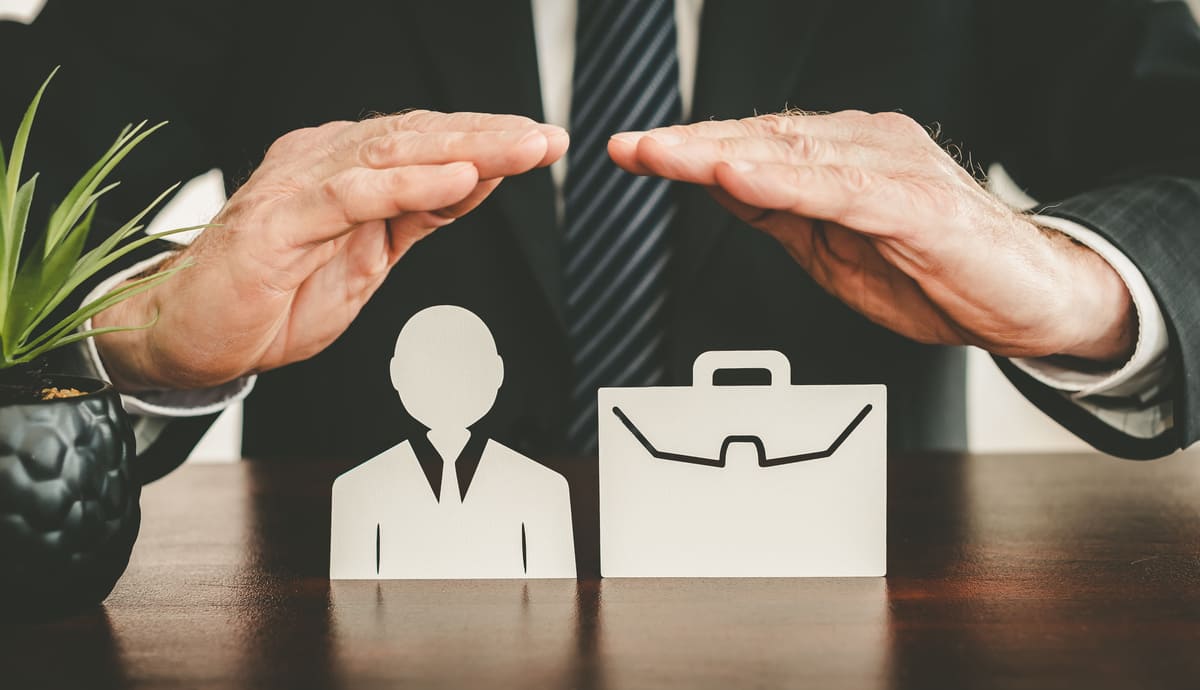 Hands making a roof over pictures of an insurance agent and briefcase